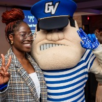 Girl takes a picture with Louie the Laker. She does a peace sign and Louie anchors up.